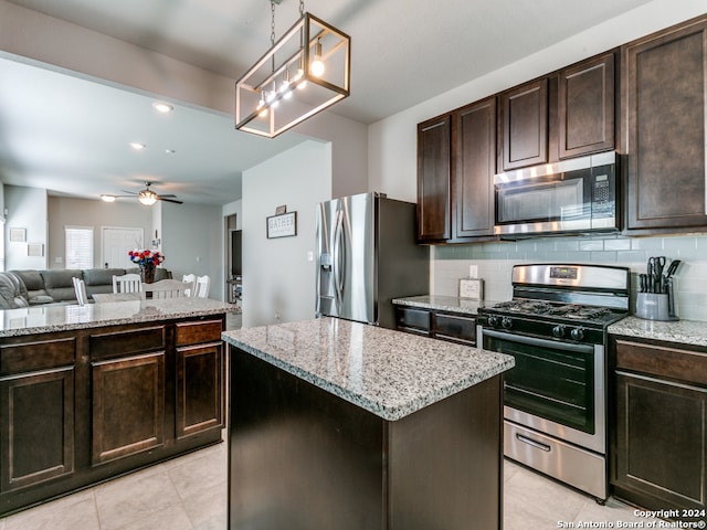 kitchen with stainless steel appliances, ceiling fan with notable chandelier, tasteful backsplash, dark brown cabinetry, and a center island