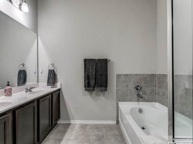 bathroom featuring dual bowl vanity, a bath to relax in, and tile flooring