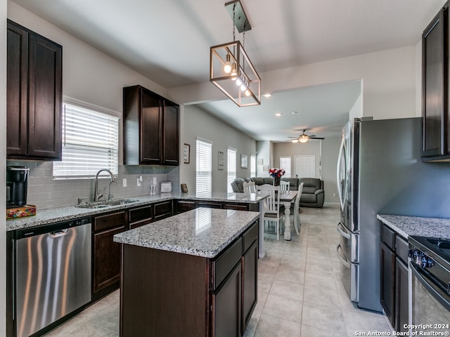 kitchen with sink, ceiling fan with notable chandelier, backsplash, stainless steel dishwasher, and pendant lighting