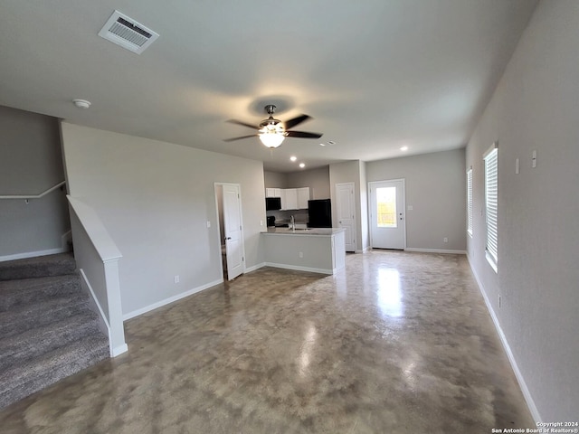 unfurnished living room featuring concrete floors, ceiling fan, and sink