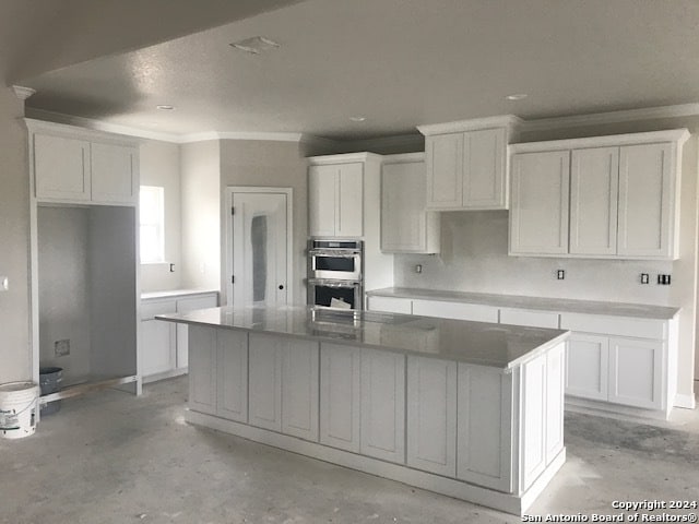 kitchen with an island with sink and white cabinets