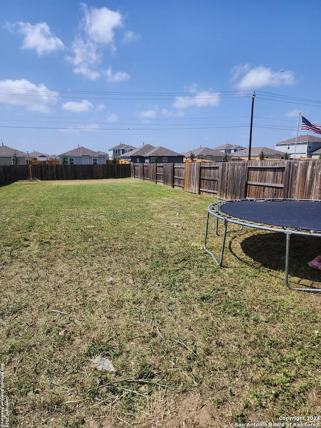 view of yard featuring a trampoline and a fenced backyard