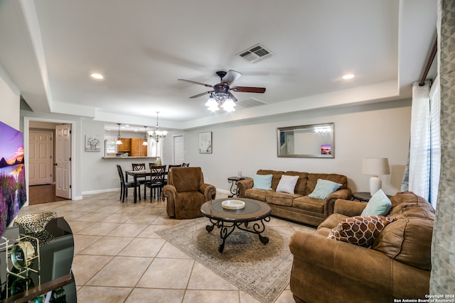 tiled living room with ceiling fan with notable chandelier