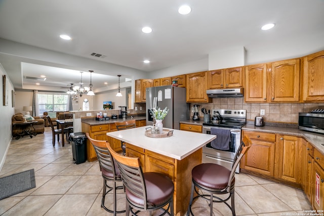 kitchen featuring stainless steel appliances, backsplash, a breakfast bar area, a kitchen island, and hanging light fixtures