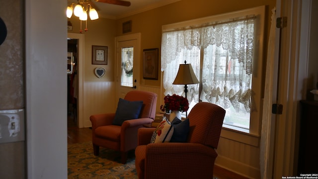 living area with crown molding, dark hardwood / wood-style floors, ceiling fan, and a healthy amount of sunlight