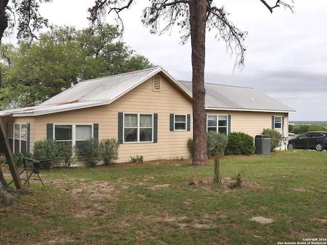 exterior space featuring central air condition unit and a lawn