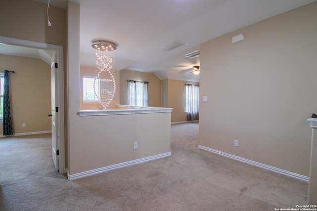 spare room with a notable chandelier, light colored carpet, and vaulted ceiling