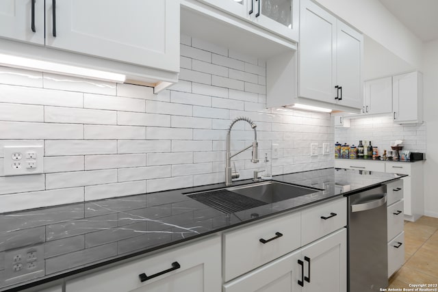 kitchen featuring dark stone counters, sink, backsplash, white cabinets, and light tile patterned floors