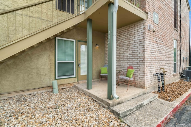 view of exterior entry featuring a patio and central AC