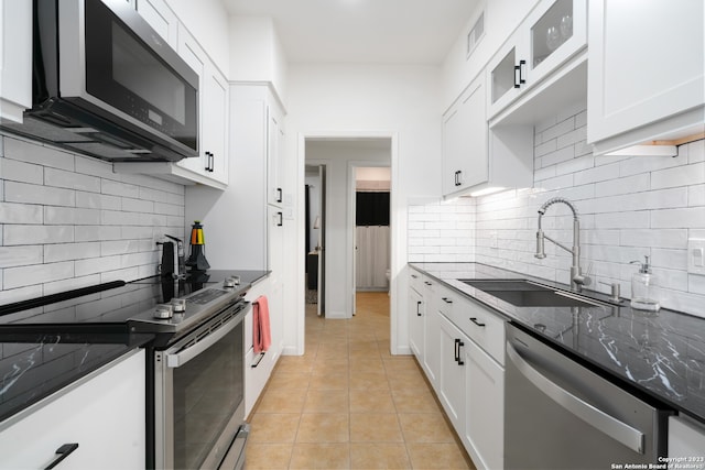 kitchen with decorative backsplash, stainless steel appliances, sink, white cabinetry, and light tile patterned floors