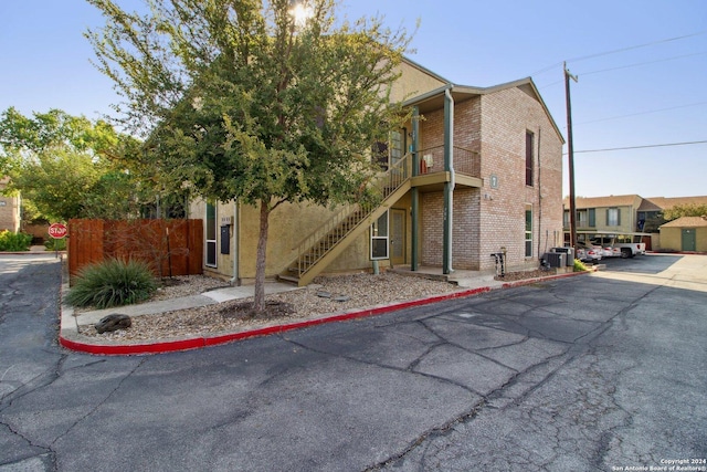 3678 Hidden Dr Unit 704, San Antonio, TX 78217 - view of building exterior featuring fence, covered parking, stairs, and central air condition unit