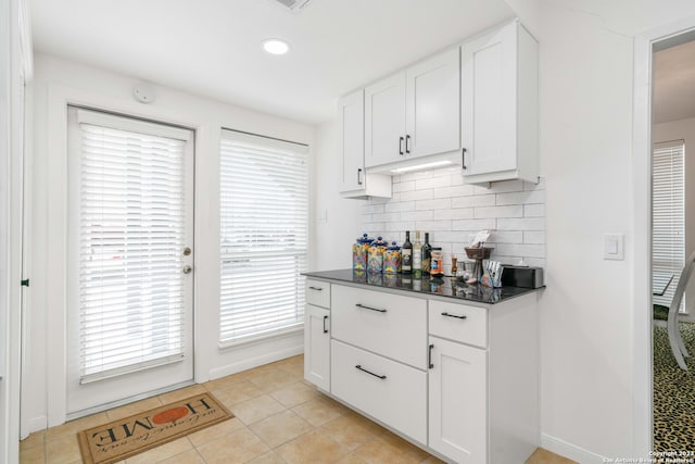 bar featuring light tile patterned flooring, decorative backsplash, and white cabinetry