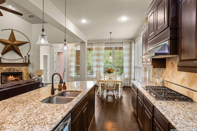 kitchen with hanging light fixtures, stainless steel gas cooktop, a fireplace, dark hardwood / wood-style flooring, and sink