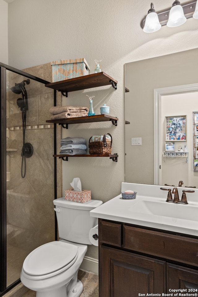 bathroom with a shower with shower door, toilet, and vanity