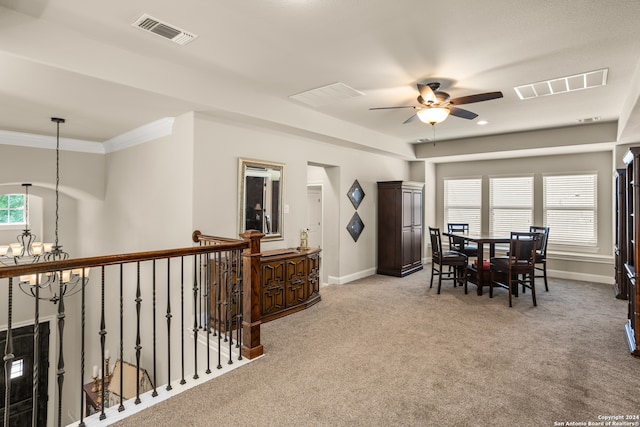 carpeted dining room with ornamental molding and ceiling fan with notable chandelier