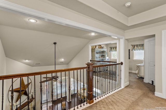 hall with vaulted ceiling and dark colored carpet