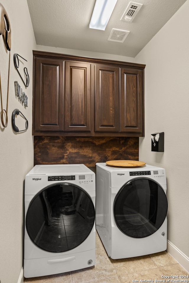 laundry room with cabinets, washer and dryer, and light tile floors