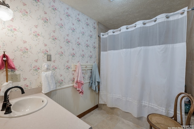 bathroom with tile floors, vanity, and a textured ceiling