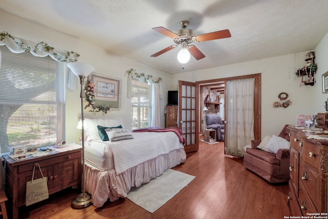 bedroom featuring ceiling fan, multiple windows, french doors, and wood-type flooring