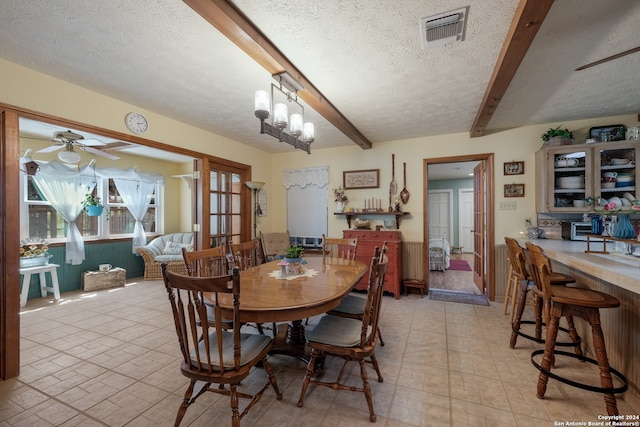 tiled dining room featuring a textured ceiling, ceiling fan with notable chandelier, and beamed ceiling