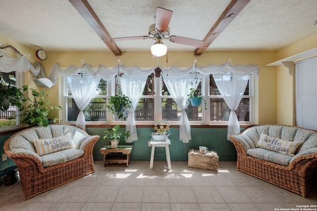 sunroom / solarium featuring ceiling fan and beam ceiling