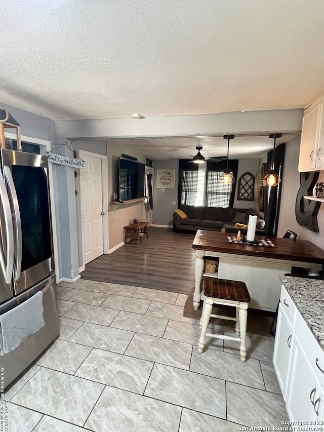 kitchen featuring a textured ceiling, light wood-type flooring, white cabinetry, and stainless steel fridge