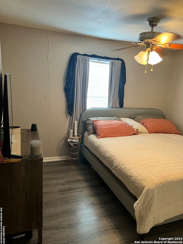 bedroom featuring a textured ceiling, ceiling fan, and dark wood-type flooring