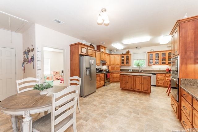 kitchen with appliances with stainless steel finishes, a center island, light tile floors, and sink