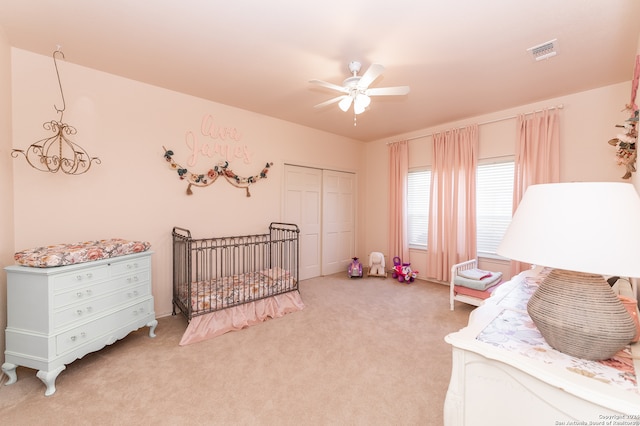 carpeted bedroom with a closet, ceiling fan, and a nursery area