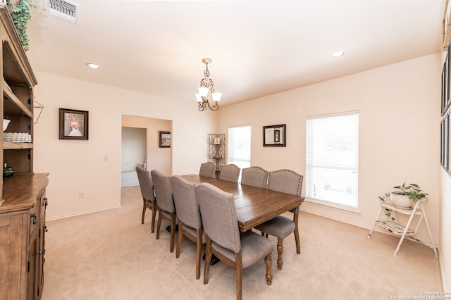 carpeted dining area with an inviting chandelier