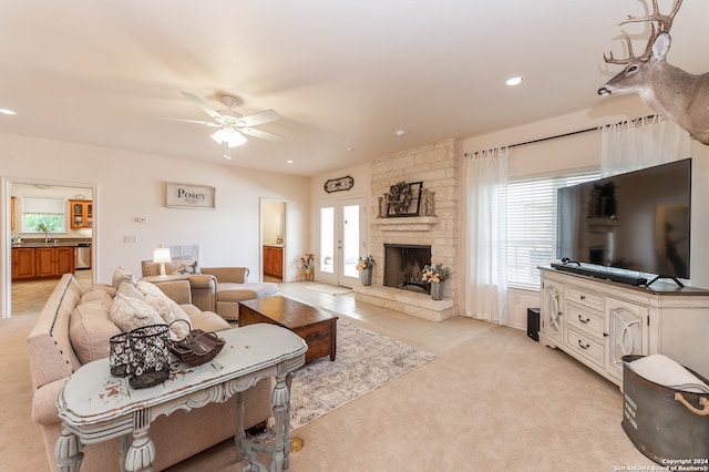 carpeted living room featuring ceiling fan, brick wall, sink, and a stone fireplace