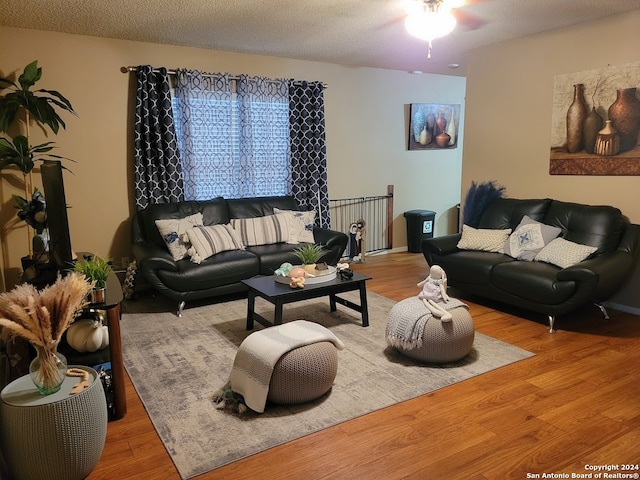 living room with a textured ceiling, ceiling fan, and hardwood / wood-style flooring