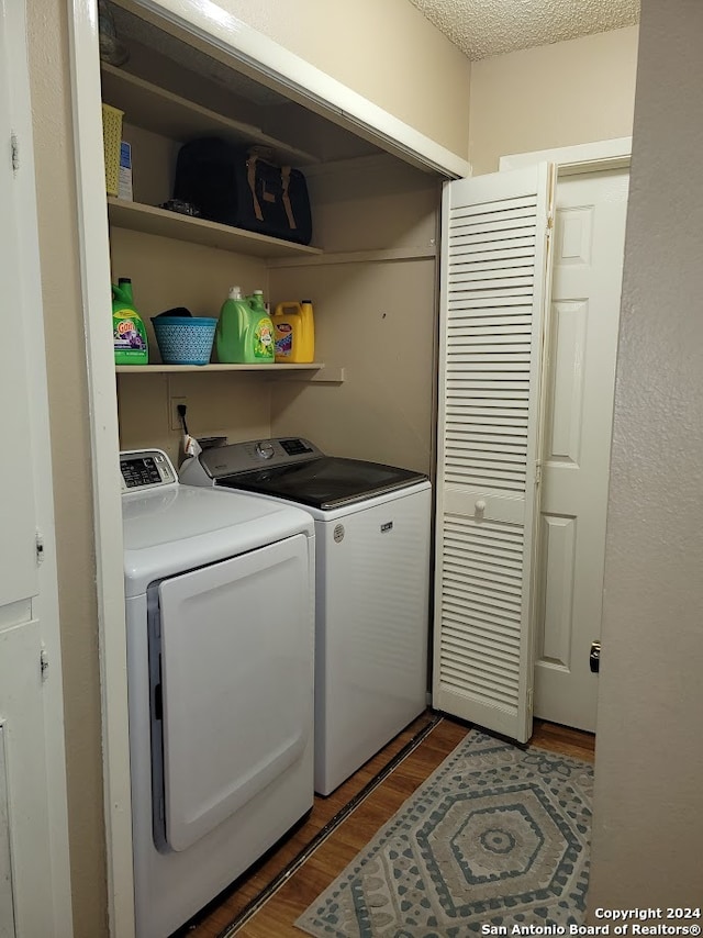 clothes washing area with washing machine and clothes dryer, dark hardwood / wood-style floors, and a textured ceiling