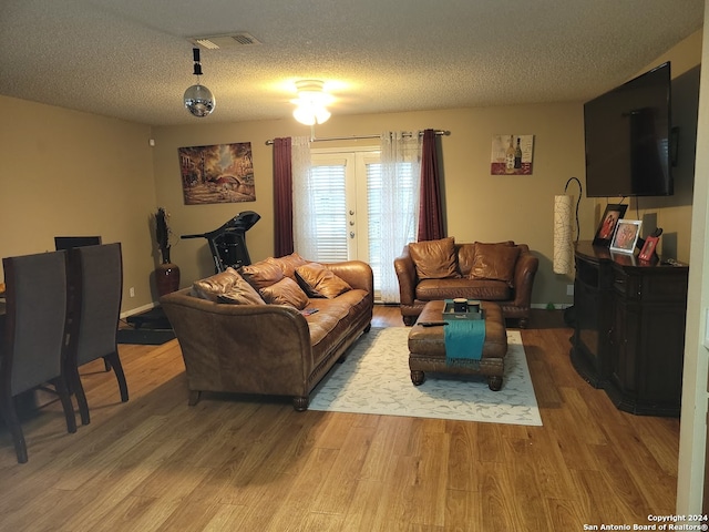 living room with a textured ceiling, french doors, and hardwood / wood-style flooring