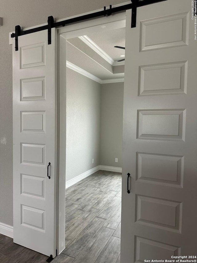 spare room with a barn door, hardwood / wood-style floors, a textured ceiling, and ornamental molding