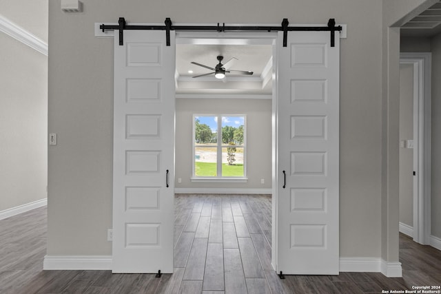 foyer entrance featuring a barn door, crown molding, hardwood / wood-style floors, and ceiling fan