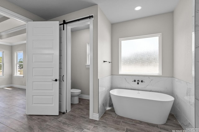 bathroom featuring a bathing tub, toilet, tile walls, and hardwood / wood-style floors