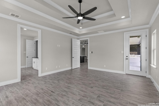 empty room featuring ceiling fan, crown molding, a tray ceiling, and light hardwood / wood-style flooring