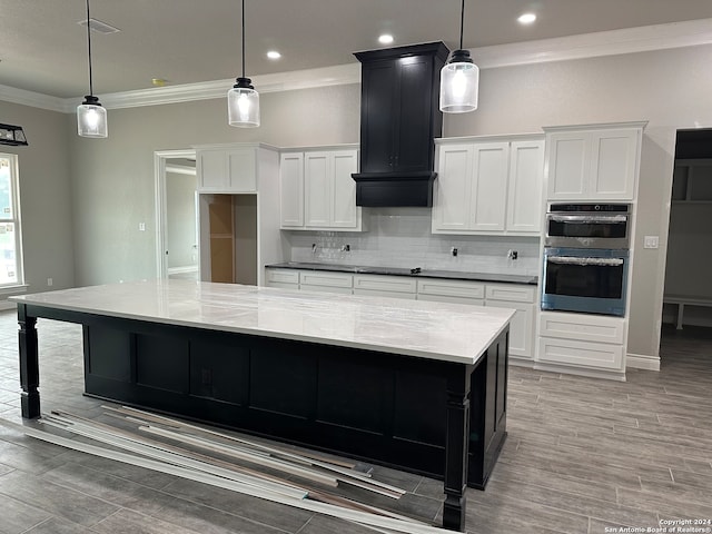 kitchen with premium range hood, white cabinets, a spacious island, hanging light fixtures, and stainless steel double oven