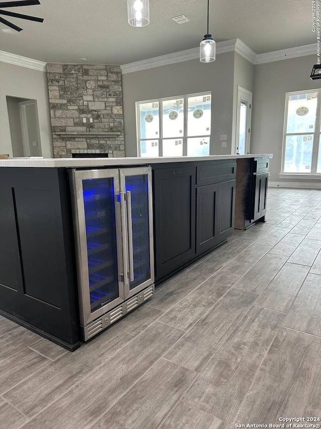 kitchen with wine cooler, light hardwood / wood-style flooring, hanging light fixtures, and ornamental molding