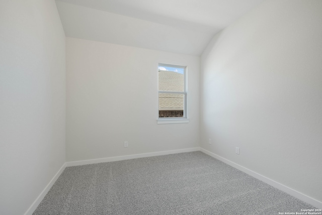 carpeted spare room featuring lofted ceiling