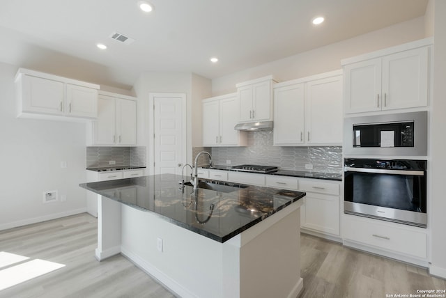 kitchen featuring an island with sink, light hardwood / wood-style flooring, stainless steel appliances, and white cabinetry