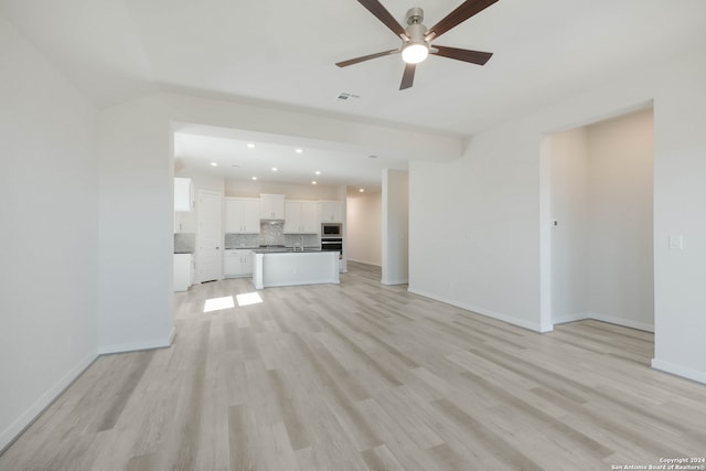 unfurnished living room featuring light hardwood / wood-style floors, sink, and ceiling fan