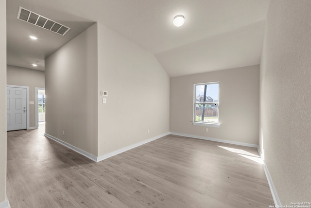 unfurnished room featuring plenty of natural light, light wood-type flooring, and lofted ceiling