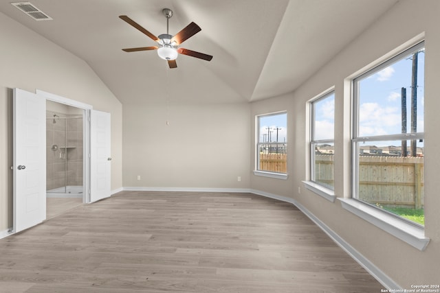 interior space with vaulted ceiling, connected bathroom, light hardwood / wood-style floors, and multiple windows