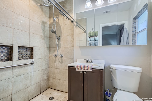 bathroom featuring tile flooring, toilet, tiled shower, and vanity