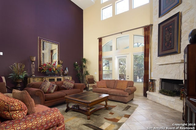 tiled living room with a premium fireplace and a high ceiling