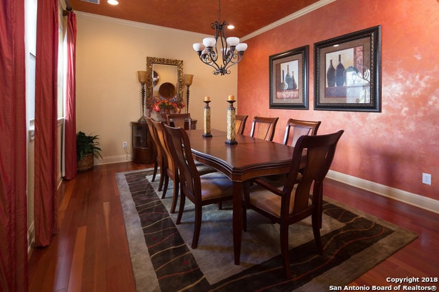 dining space with crown molding, an inviting chandelier, and dark wood-type flooring