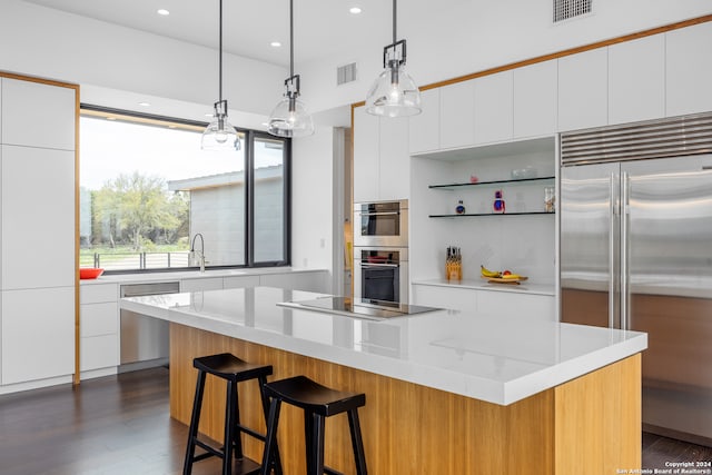 kitchen with white cabinetry, dark hardwood / wood-style flooring, a kitchen island, hanging light fixtures, and appliances with stainless steel finishes