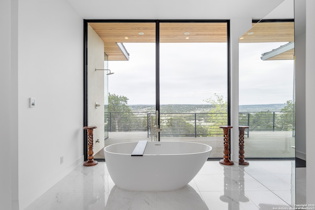 bathroom featuring floor to ceiling windows and a bathtub